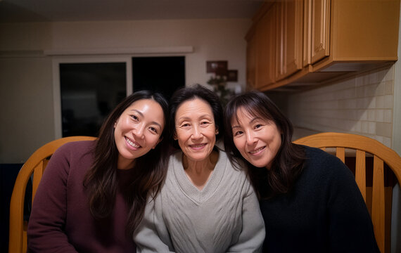 Three Asian women of different generations smiling together indoors family portrait