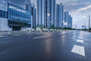 Fototapeta premium Empty urban asphalt road passing through a modern residential district with high rise apartment buildings.
