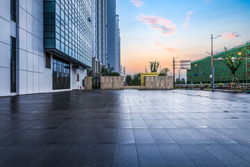 Empty wet square floor and modern commercial office buildings in a new development district.