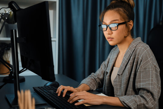 Beautiful businesswoman working on laptop for marketing plan on social media online, searching data report at over late night time at modern home office, working startup company project job. Infobahn.