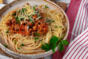 Bolognese pasta with haddock fish mince served with parmesan cheese on ceramic plate. Pescatarian meal. Variation of the classic Italian dish