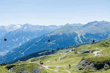 Cable cars transporting people over green mountains in summer