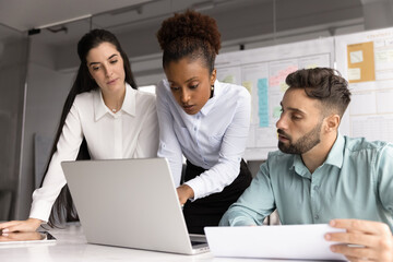 Focused millennial businesswoman teach diverse staff planning on notebook screen