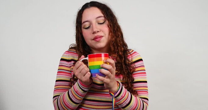 Young woman enjoying a drink in a rainbow mug isolated on a white background
