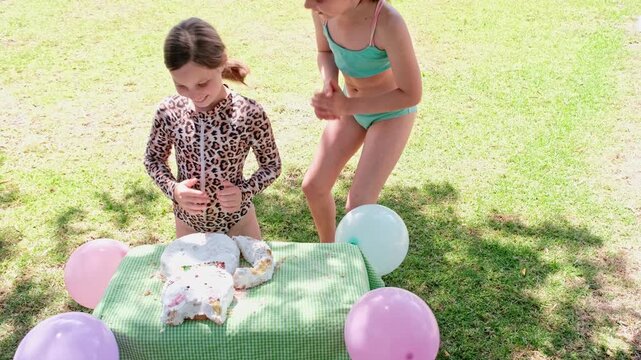 Seated birthday girl gets face pushed into cake by funny sister after song