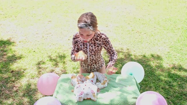 Young girl eats birthday cake in messily using hands and shoving it in mouth