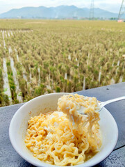 Delicious Warm Instant Noodles With Egg Enjoyed Outdoors Overlooking Harvested Rice Field
