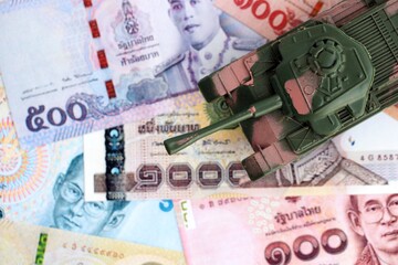 Thai baht currency money bills and toy tank close up. The concept of army funds and weapons sales