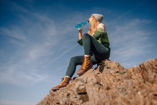 Woman hiker drinking sports drink on mountain top - Powered by Adobe