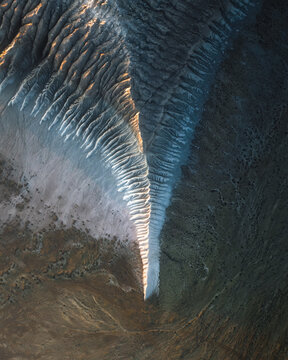 Aerial view of stark white formations cut through the rugged terrain, where the sun casts long shadows across the landscape, Sor Tuzbair, Mangystau Region, Kazakhstan.