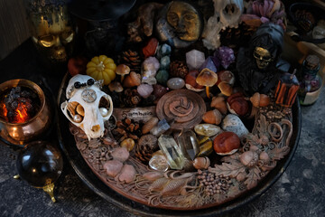 wiccan altar with wheel of the year on dark table close up. animal skull, witch cauldron, amulets,...