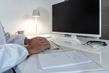 Healthcare professional's hands actively typing on a keyboard, with medical notes and equipment nearby, symbolizing digital efficiency in medicine