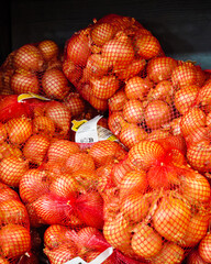 Onion vegetables on market stall. Onions pack net on supermarket shelf.