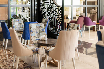 Seating area in a contemporary cafe features colorful chairs and a tastefully designed ambiance. A combination of patterns and textures creates a warm, inviting space for relaxation and socializing