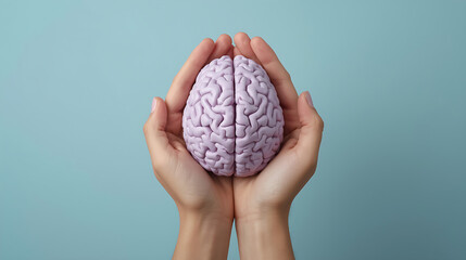 A pair of hands is depicted holding a light purple anatomical brain model against a pastel blue background, representing themes of mental health, mindfulness, and cognitive care.