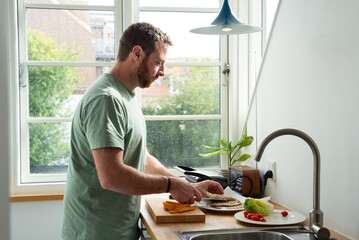 Man preparing lunch in a Danish style kitchen.