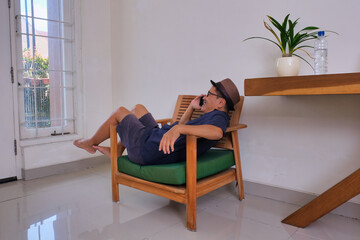man casually lying on the armchair, making a phone call