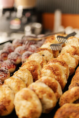 A variety of freshly baked pastries are arranged neatly on a tray in a bakery. The warm golden crusts and sweet toppings create a tempting sight for morning customers