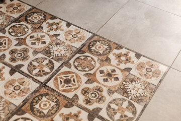 Beautiful ceramic tiles cover the floor, showcasing a mix of patterns in warm colors. The design integrates vintage aesthetics into a contemporary space, creating an inviting atmosphere