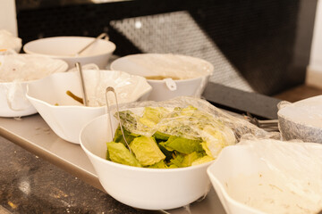 A selection of fresh lettuce and various toppings is displayed in bowls at a food bar. Diners can choose their favorites during the busy lunch hour