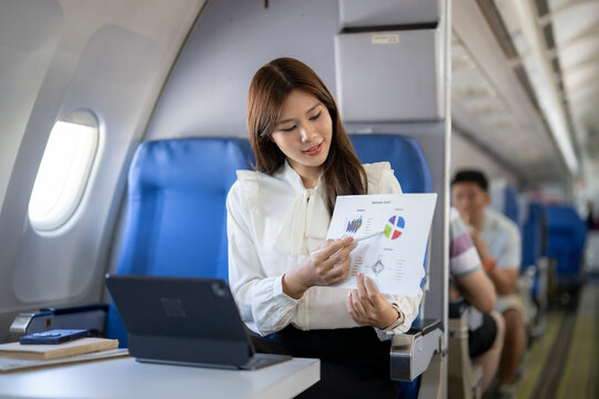 Woman presenting business report flying on airplane - Powered by Adobe