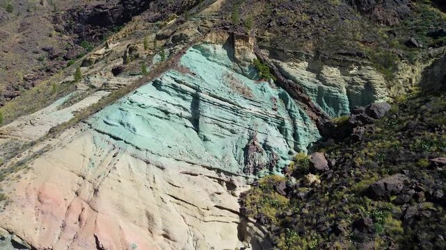 close-up aerial drone view of the unique Los Azulejos de Veneguera in Gran Canaria, emphasizing the striking turquoise, green, and yellow layers of hydrothermally altered volcanic rock