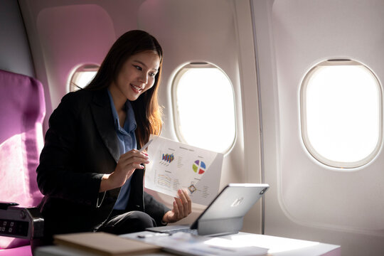 Businesswoman having video call presenting report graph on airplane - Powered by Adobe