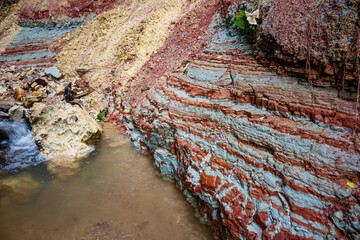 Striking colorful clay layers from the Carboniferous period, exposed in a rugged gully next to a flowing brook