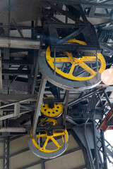 Engineering structure: a system of pulleys and cables for moving a lift cabin. Old industrial mechanism, close-up of a multi-ton yellow wheel