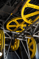 Close-up of a funicular mechanism: bright yellow pulleys and steel beams