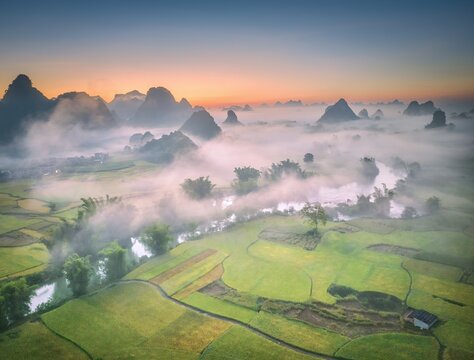 Aerial view of the Ban Gioc Detian Falls area shrouded in ethereal mist, with karst mountains piercing through, Cao Bang, Vietnam.