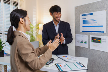 Two colleagues celebrate a successful discussion with cheerful expressions and clapping. Their positive interaction reflects teamwork, motivation, and satisfaction after reviewing reports.