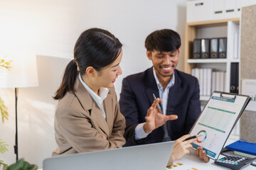 Two business professionals are discussing financial charts and reports in a modern office. They collaborate, share ideas, and analyze data together, highlighting teamwork and strategy.