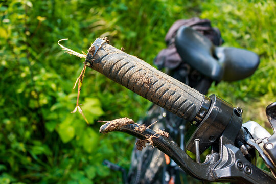 Grimy bicycle grip and brake lever, caked in mud and debris after a gnarly trail ride. A classic shot of a well-used off-road machine, ready for more