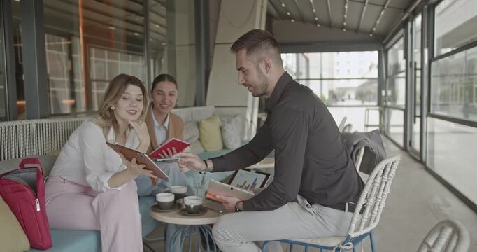 A team of dedicated business partners collaborates in an outdoor cafe, discussing innovative strategies and analyzing data for the successful growth of their small business.