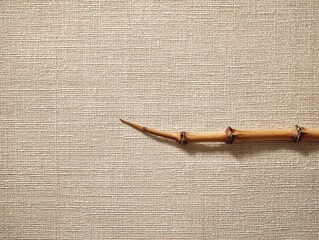 Natural Bamboo Stick on Textured Beige Fabric Background Minimalist Composition Neutral Tones Organic Material Rustic Decor Serene Surface Element Asian Inspired Design Horizontal