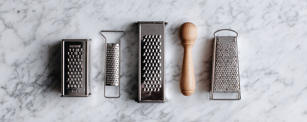Culinary tools. Assorted graters on marble convey kitchen prep, cooking variety, or gourmet food themes. Useful for blogs, ads, cookbooks  culinary projects.