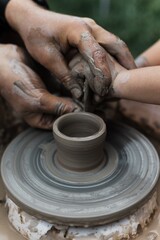 A master guides children's hands as they sculpt on a pottery wheel. Creativity, learning, and experiencing craft through experience.