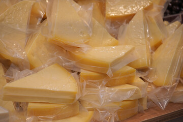Cheese slices stacked in clear packaging at a market stall
