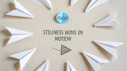 White paper airplanes surrounding a focus sign with motivational quote stillness wins in motion