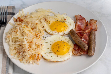 fried eggs served with sausage and bacon