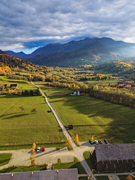 Aerial view of a sunlit valley casting long shadows, with the Bucegi Mountains looming in the distance, Strada Gl&Auml;&fnof;j&Auml;&fnof;rie R&Atilde;&cent;ul Mare, R&Atilde;&cent;&Egrave;&trade;nov, Jude&Egrave;&rsaquo;ul Bra&Egrave;&trade;ov, Romania.