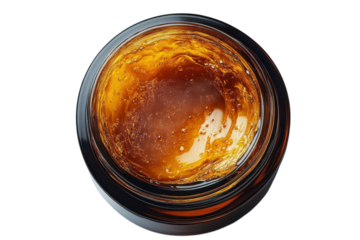 Golden cannabis concentrate in a glass jar showcases its rich amber color and potent therapeutic properties on transparent background
