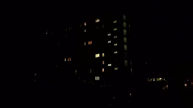 Residential building with illuminated windows without street lighting during a blackout due to power outage in a Kyiv district.