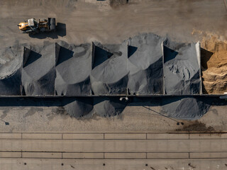 Aerial view of stark geometric patterns formed by piles of gravel and sand, juxtaposed against the pale concrete and heavy machinery, Berlin, Germany.