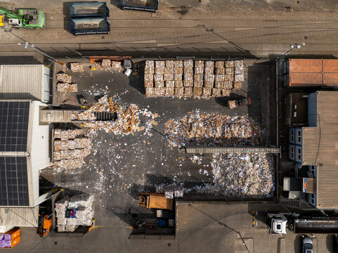 Aerial view of a recycling plant where bales of paper, cardboard, and loose paper create a textured landscape of whites and browns, Berlin, Germany.