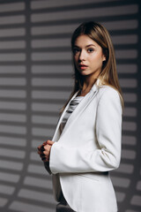 Fototapeta premium Young business woman wearing white suit standing isolated on grey background