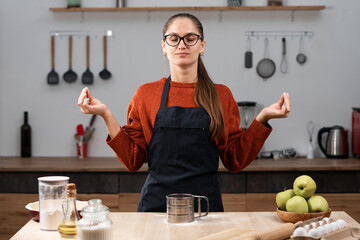 Portrait of woman wearing apron cooking apple pie enjoy making clean food meditating in yoga pose in kitchen at home. baking, cookies and dessert.