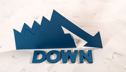 青い切紙で作られたグラフが鋭く下降しdownの文字に突き刺さる象徴的構図