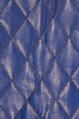 Obraz premium A detailed vertical close-up of a dark navy blue, textured faux leather surface featuring a continuous diamond-shaped quilted stitching pattern, suitable for a background